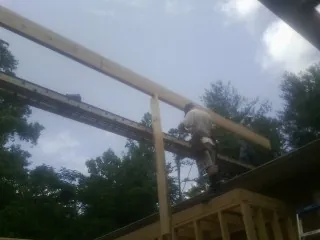 Carpenter setting a ridge beam over a new addition frame — Ice Dam Removal by Roofing Brothers in Laura