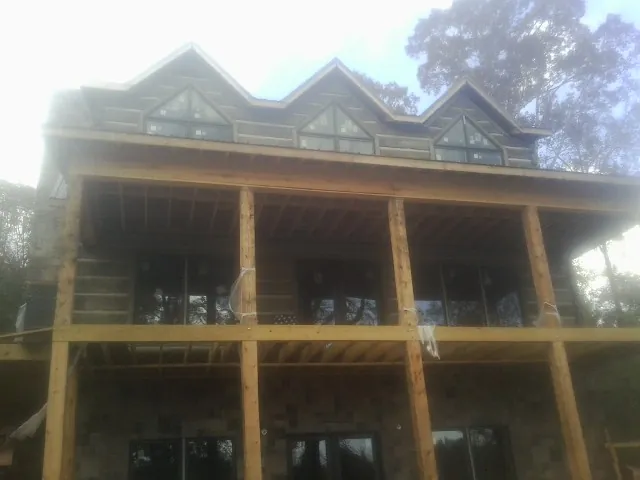 Dormers and porch framing on a large log home under construction — Roof Coating work by our crew in Laura